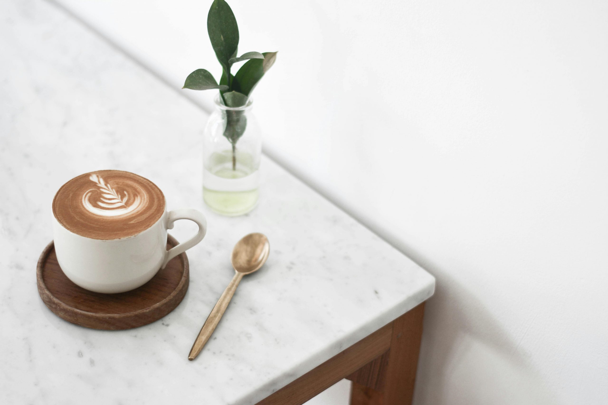 cup of coffee with latte art placed on a wooden coaster
