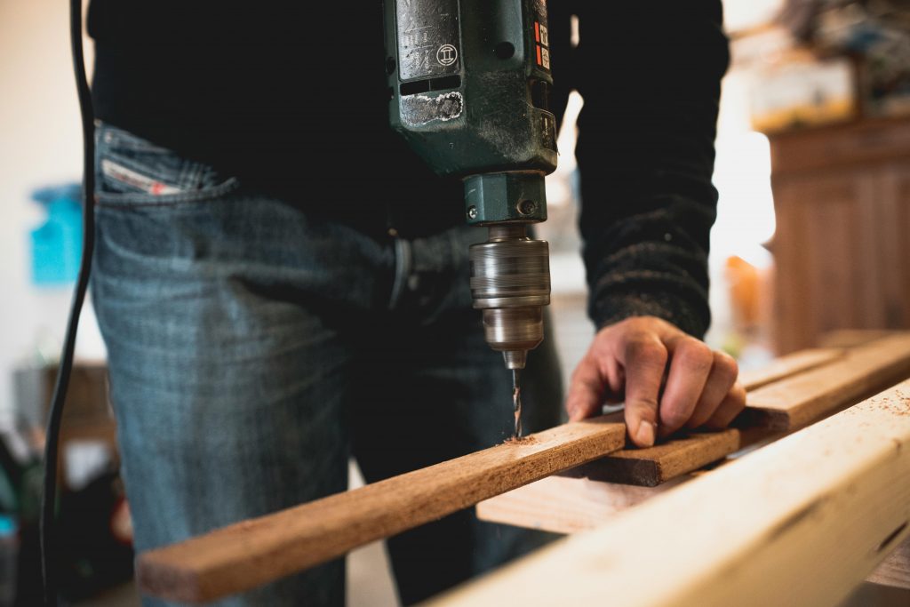man using a drill to make a hole in a piece of wood