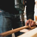 man using a drill to make a hole in a piece of wood