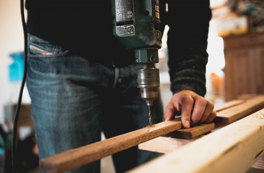man using a drill to make a hole in a piece of wood
